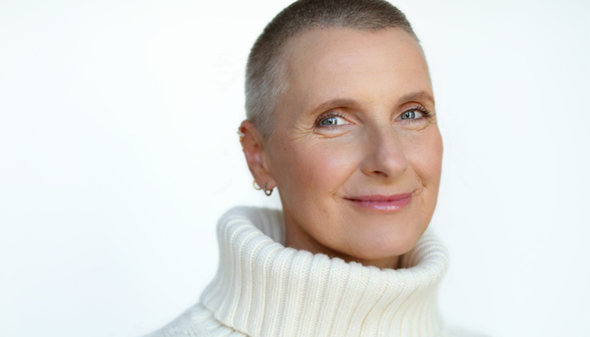 Elizabeth Gilbert Wearing A White Turtleneck And Smiling Against A White Background