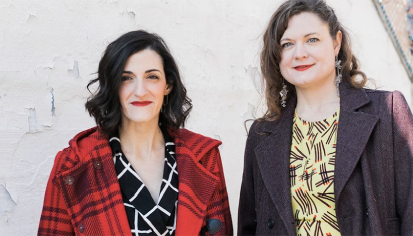 Sweater Set Duo Wearing Coats And Standing Front Of A White Wall