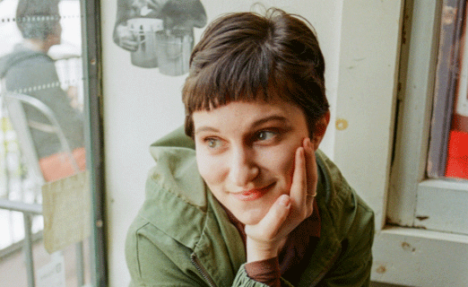 Angela Sclafani With Her Chin In Her Hand Sitting By A Coffee Shop Window