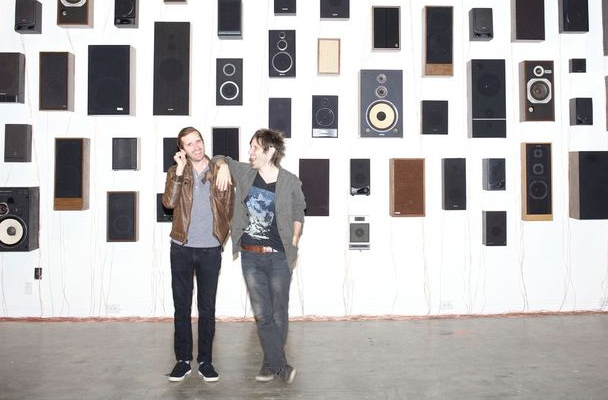 The Holladay Bros Standing In A Warehouse With Audio Equipment On The Wall