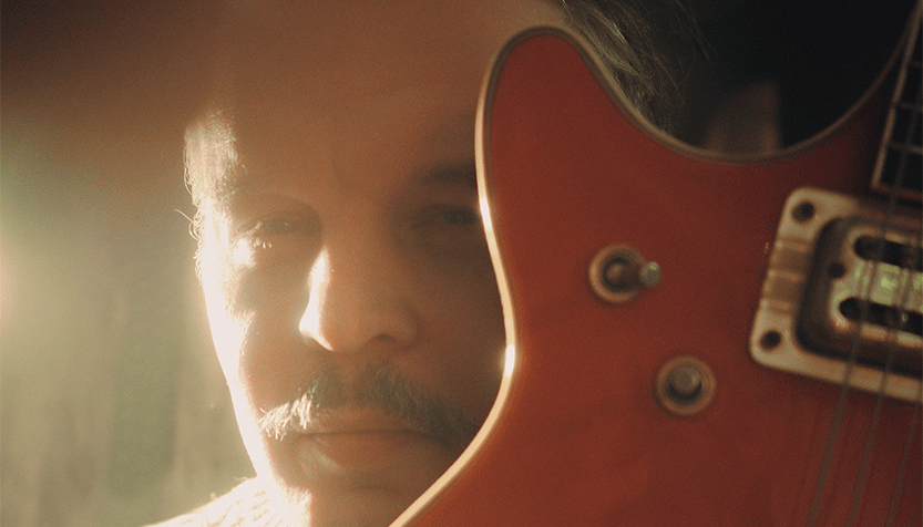 Tallest Man On Earth Closeup Up His Face In The Sunlight Behind A Guitar